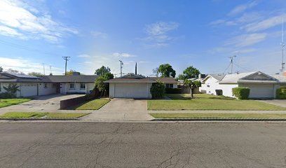 Hanford, CA home bought by Varo as-is: row of single-story ranch-style homes with garages and green lawns
